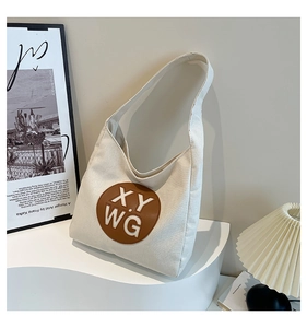 Detail of off-white canvas tote bag with circular leather patch and XY WG lettering