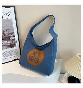 Detail of blue canvas tote bag with brown leather patch and XY WG lettering