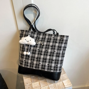 Black and white checkered tote bag with bow prints and a plush cloud charm on stone base