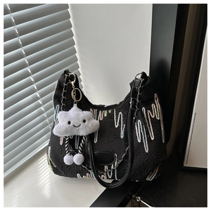 Détail du sac bandoulière noir brodé avec motifs ondulés et breloque nuage en peluche