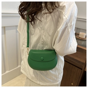 Grass green saddle crossbody bag shown on model with adjustable strap and smooth finish