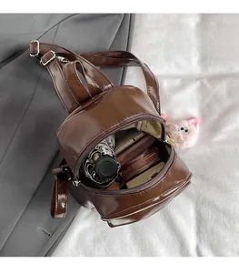 Detail view of mini brown backpack interior storage with small umbrella and plush charm