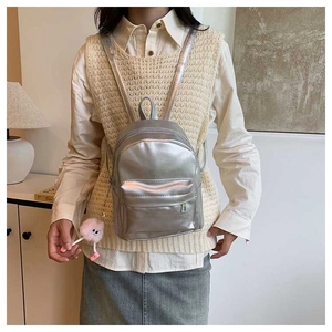 Silver metallic mini backpack for women featuring a pink plush eye keychain on back