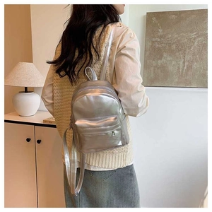 Vue arrière d'un mini sac à dos argenté porté par un mannequin dans un intérieur chic
