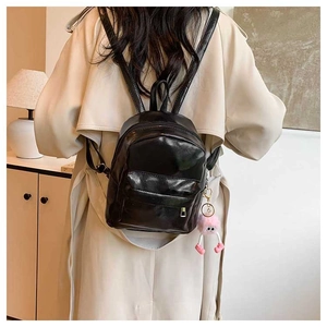 Détail du mini sac à dos en similicuir noir avec peluche rose sur le dos du mannequin