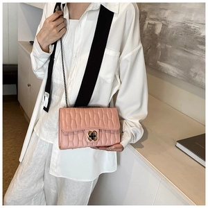 Detail of pink quilted crossbody bag with floral clasp and black chain strap