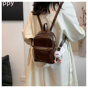 Mini sac à dos marron brillant avec zips argentés et pendentif peluche rose