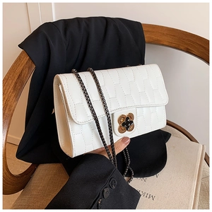 Macro shot of white quilted crossbody bag with floral metal clasp and gunmetal chain