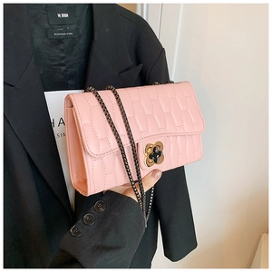 Detail of pink quilted shoulder bag featuring a dark chain strap and floral buckle