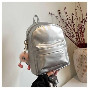 Détail d'un mini sac à dos argenté métallisé avec pendentif en peluche rose