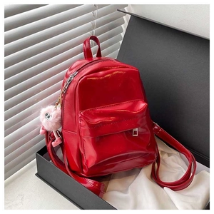 Detailed close-up of a glossy red patent leather mini backpack with a pink plush charm