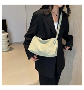 Detail of light green pleated tote bag with wrinkled texture worn over a black blazer