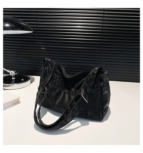 Close-up of the black pleated texture and silver metal buckle on this large shoulder bag