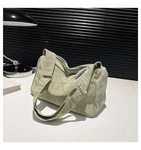 Detailed texture of light green nylon tote bag with pleated fabric and rope zipper pull