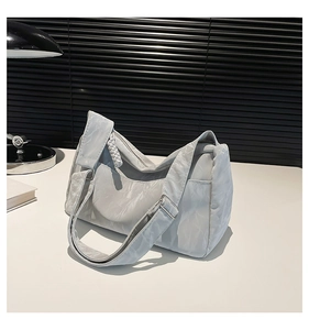Detail of light gray pleated hobo bag with wide adjustable strap and knotted detail