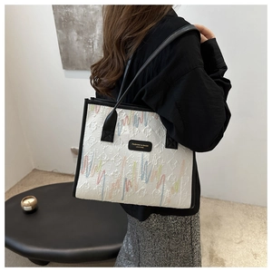 Detail of white tote bag with quilted diamond pattern and colorful wavy line embroidery