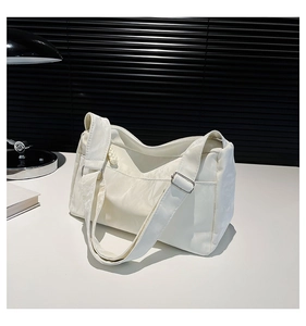 Detail of cream white textured shoulder bag with adjustable silver buckle strap