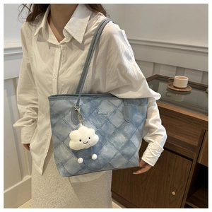 Close-up of blue and white gradient quilted tote bag with a cloud plush pendant