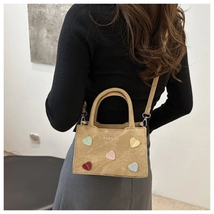 Detail of a brown suede bag with colorful heart patches and printed FASHION logo