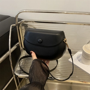 Classic black saddle bag in matte leather finish with gold hardware and slim strap