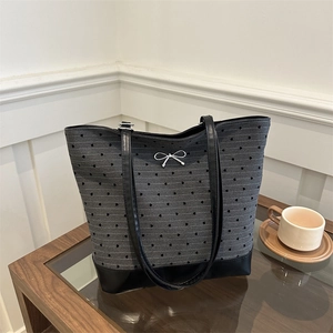 Grey canvas tote bag with black heart patterns and a silver bow on a wooden table