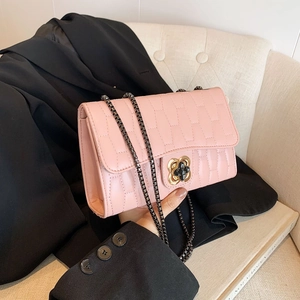 Pink quilted chain crossbody bag featuring a golden floral clasp on a black blazer jacket