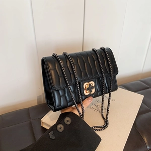 Quilted wave pattern crossbody bag with a decorative floral clasp and elegant box chain