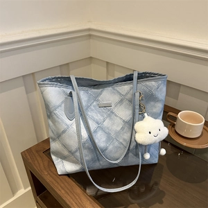 Blue denim tote bag with quilted pattern and plush cloud charm on a wooden table