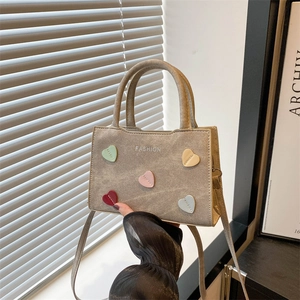 Khaki mini handbag with multicolor heart decor and FASHION text in a warm setting