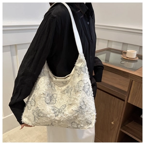 Detail of white canvas tote bag featuring lace butterfly embroidery and textured fringe