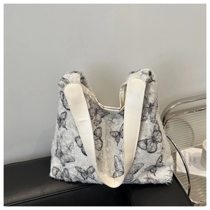 Close-up of canvas tote bag featuring black butterfly prints and white leather handle detail