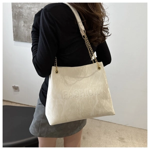 Détail du sac cabas crème avec gaufrage fashion et bandoulière en chaîne dorée