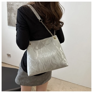 Detail of grey tote bag featuring pleated texture and embossed FASHION lettering with chain strap