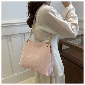 Détail du sac rose avec lettrage embossé et bandoulière en chaîne dorée élégante