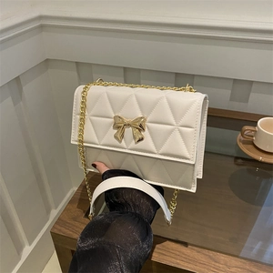 White quilted crossbody bag with gold bow clasp and metal chain strap for women