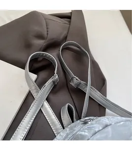 Detail of silver gray backpack with wrinkled metallic texture and adjustable straps