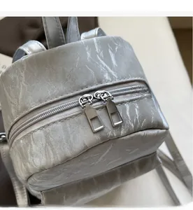 Detail of silver-grey backpack showing smooth dual metal zippers and marble texture
