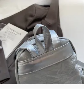 Detailed shot of reinforced handle and metallic pleated texture on silver backpack