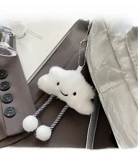 Close-up of a white plush cloud charm with a smiling face on a minimalist backpack