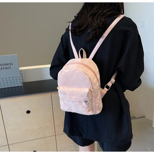 Close-up of pink mini backpack with pleated texture and adjustable shoulder straps