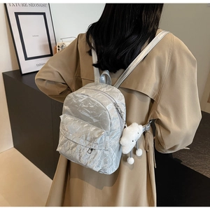 Detail van zilveren metalen mini-rugzak met pluche wolkenhanger op een model
