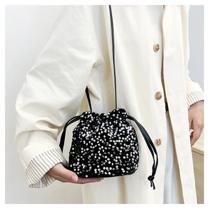 Détail d'un sac seau noir à paillettes avec fermeture à cordon et fine bandoulière