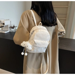 Witte mini rugzak met wolkenhanger gedragen door een model in een gezellig café