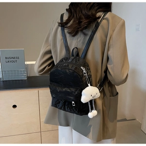 Close-up of black wrinkled texture mini backpack with a cute white cloud plush charm