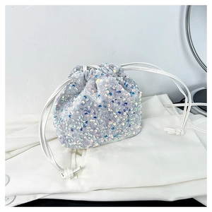 Gros plan sur les paillettes argentées d'un sac seau à cordon avec une fine bandoulière