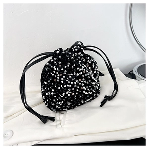 Détail d'un sac seau noir à paillettes avec des reflets argentés et cordon de serrage