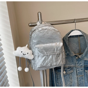 Detail van zilveren mini-rugzak met kreukeleffect en een witte wolk pluche sleutelhanger