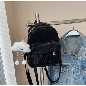 Detail of black pleated velvet mini backpack with a cloud plush pendant and texture