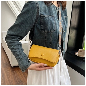 Detailed close-up of bright yellow crossbody bag with ethnic patterned wide strap