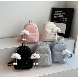 Detailed display of five colorful glossy velvet mini backpacks on marble steps